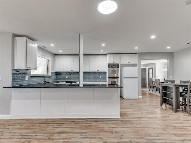 kitchen featuring white cabinets, light wood-type flooring, kitchen peninsula, and white fridge