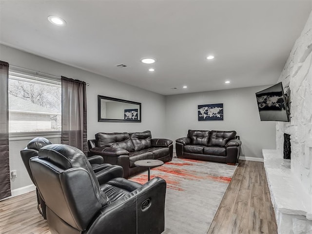 living room with light wood-type flooring and a stone fireplace