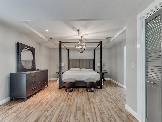 bedroom with light wood-type flooring and an inviting chandelier