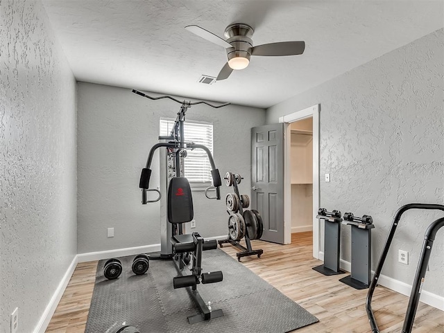 exercise room with light hardwood / wood-style floors and ceiling fan