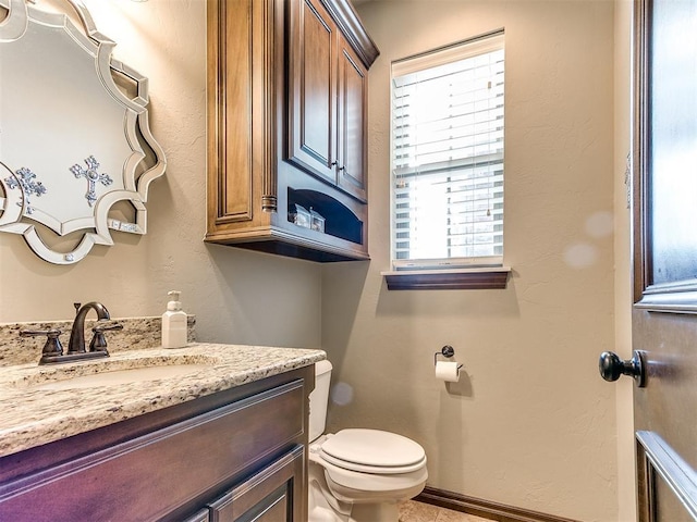 half bath featuring toilet, vanity, and baseboards