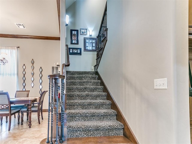 stairway with ornamental molding, visible vents, and baseboards