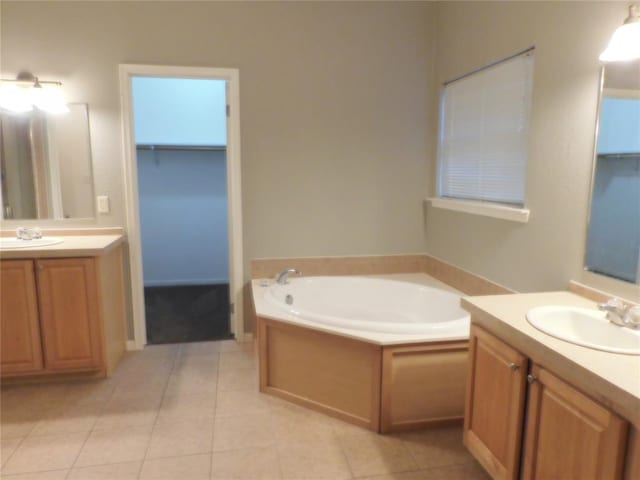 bathroom with tile patterned floors, a tub to relax in, and vanity