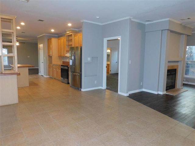 kitchen featuring ceiling fan, a breakfast bar, stainless steel fridge with ice dispenser, ornamental molding, and range