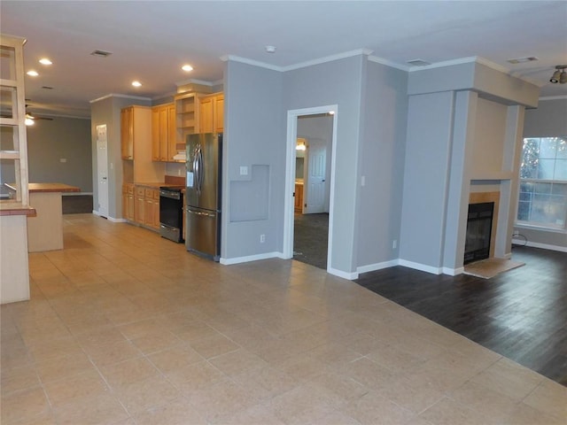 kitchen with ceiling fan, a tile fireplace, stove, crown molding, and stainless steel fridge