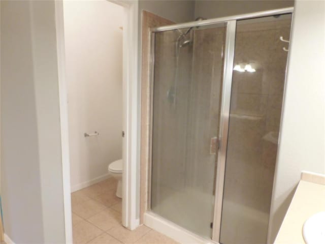 bathroom with toilet, a shower with door, vanity, and tile patterned flooring