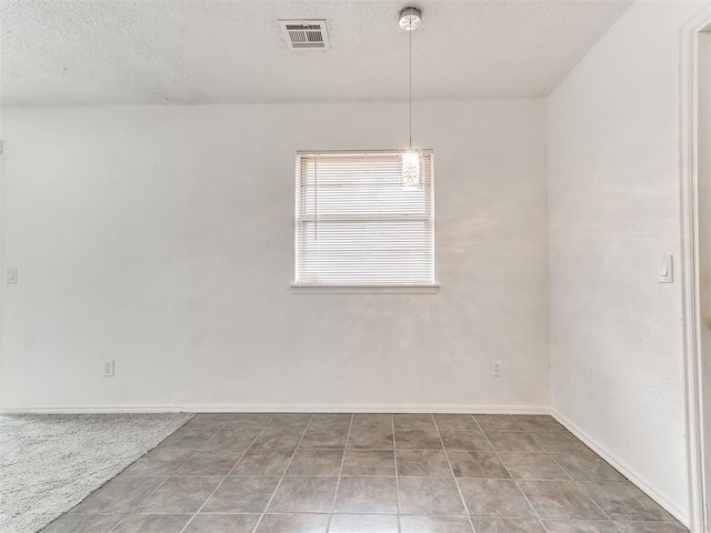 spare room featuring tile patterned floors and a textured ceiling