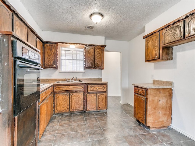 kitchen featuring sink, black oven, and a textured ceiling