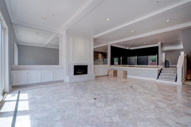 unfurnished living room with a premium fireplace, beam ceiling, and crown molding