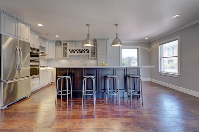 kitchen with pendant lighting, backsplash, a breakfast bar, a kitchen island, and stainless steel refrigerator