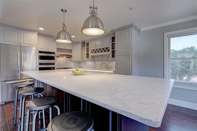 kitchen featuring crown molding, hanging light fixtures, dark hardwood / wood-style flooring, appliances with stainless steel finishes, and decorative backsplash