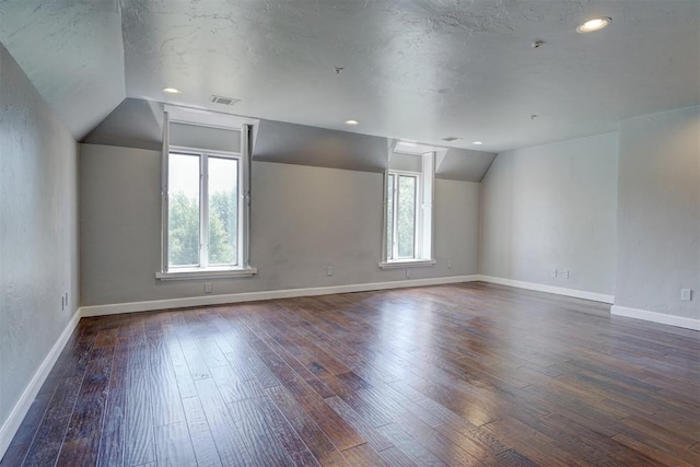 spare room with dark wood-type flooring, a textured ceiling, and lofted ceiling