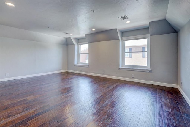 empty room featuring dark wood-type flooring, a textured ceiling, and vaulted ceiling