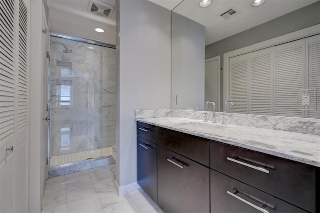 bathroom featuring a shower with shower door and vanity