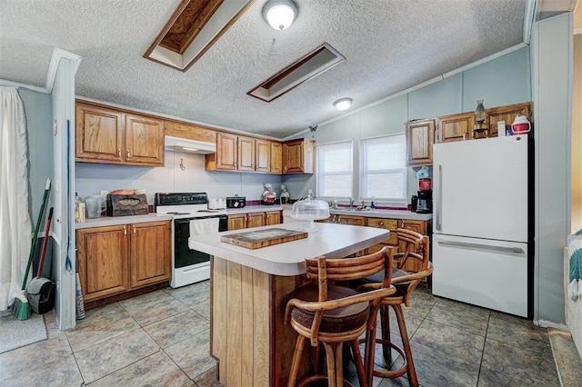 kitchen with vaulted ceiling, a kitchen bar, a center island, crown molding, and white appliances