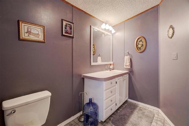 bathroom featuring ornamental molding, vanity, toilet, and a textured ceiling