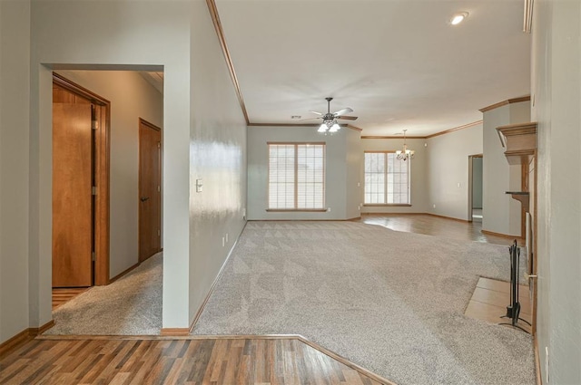 carpeted empty room with ornamental molding and ceiling fan with notable chandelier