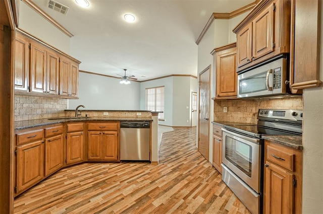 kitchen with sink, ornamental molding, kitchen peninsula, stainless steel appliances, and light hardwood / wood-style floors