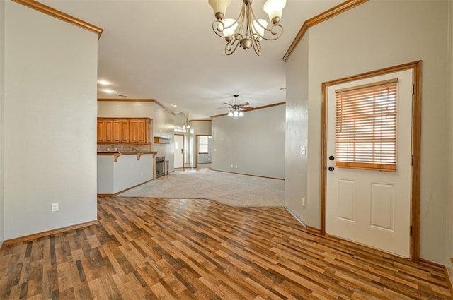 unfurnished living room featuring hardwood / wood-style flooring, ornamental molding, plenty of natural light, and ceiling fan with notable chandelier