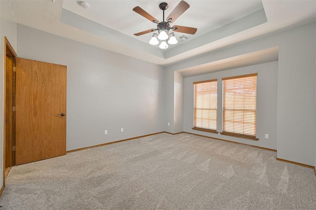 carpeted empty room featuring a raised ceiling and ceiling fan