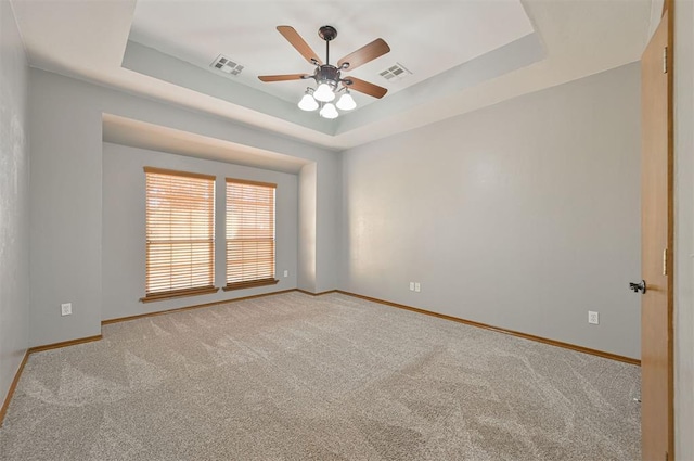 empty room featuring carpet flooring, ceiling fan, and a tray ceiling