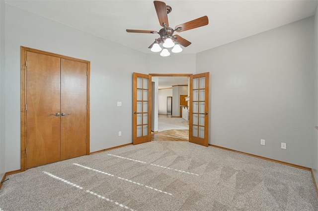 unfurnished bedroom with light carpet, a closet, french doors, and ceiling fan