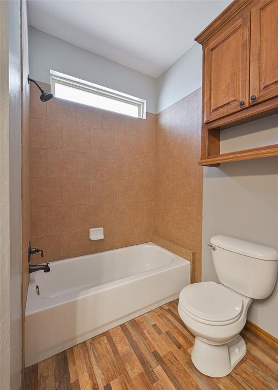 bathroom featuring toilet, tiled shower / bath combo, and hardwood / wood-style floors