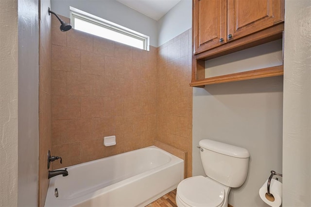 bathroom featuring toilet, tiled shower / bath combo, and hardwood / wood-style floors