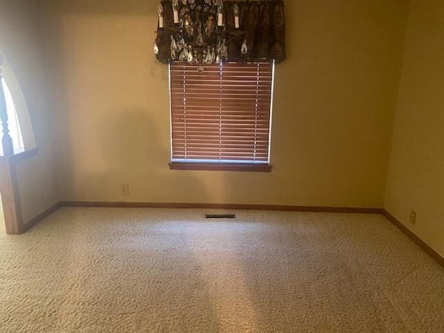 spare room with carpet floors and an inviting chandelier