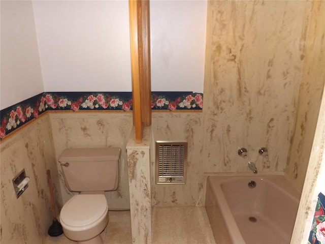 bathroom with a tub to relax in, heating unit, and toilet