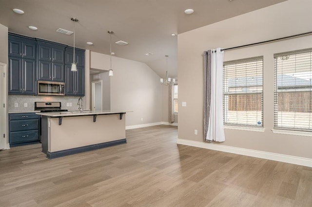 kitchen with tasteful backsplash, a kitchen island with sink, a kitchen breakfast bar, pendant lighting, and stainless steel appliances