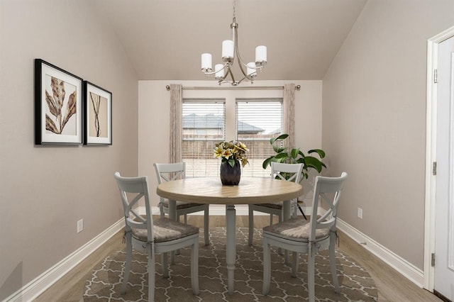 dining room with wood-type flooring, lofted ceiling, and an inviting chandelier