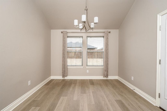 unfurnished dining area with a notable chandelier, vaulted ceiling, and light hardwood / wood-style flooring