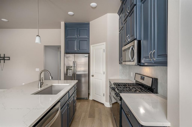 kitchen with sink, stainless steel appliances, blue cabinetry, and pendant lighting