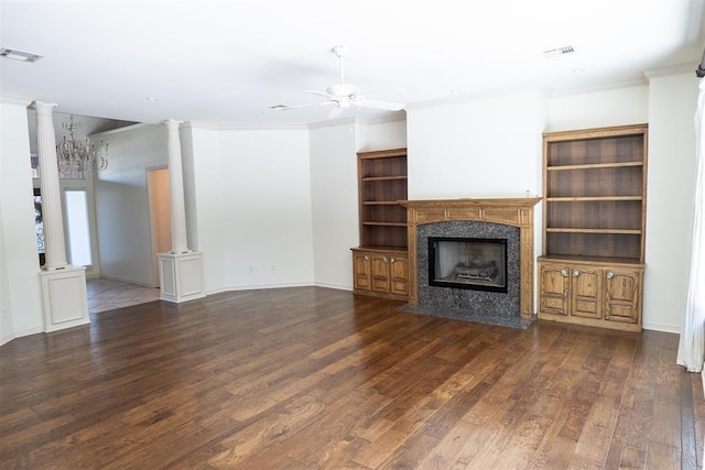 unfurnished living room featuring dark wood-type flooring, ornate columns, a fireplace, ornamental molding, and ceiling fan