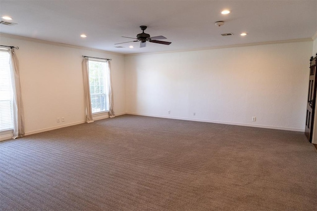 empty room featuring ceiling fan, dark carpet, and crown molding