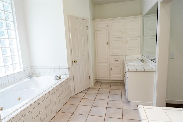 bathroom with tiled tub, vanity, and tile patterned flooring