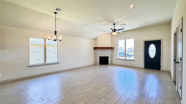 unfurnished living room with a fireplace, plenty of natural light, ceiling fan with notable chandelier, and lofted ceiling