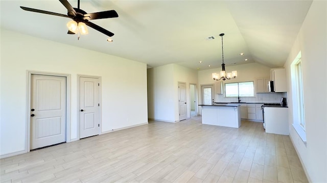 kitchen featuring range, decorative backsplash, pendant lighting, white cabinets, and a center island