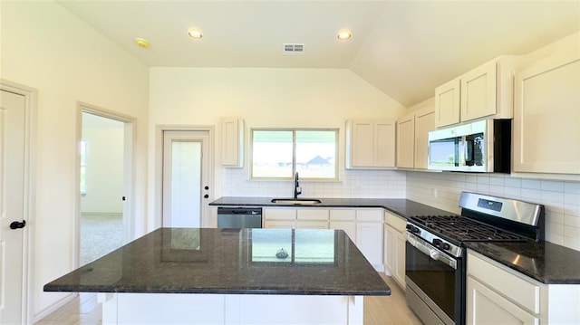 kitchen featuring appliances with stainless steel finishes, white cabinets, tasteful backsplash, and a center island