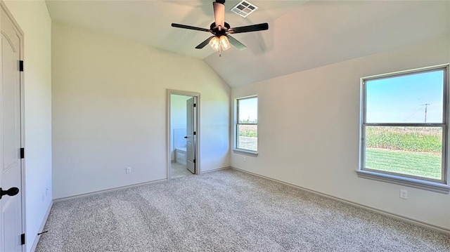 unfurnished bedroom featuring vaulted ceiling, ceiling fan, multiple windows, and ensuite bath