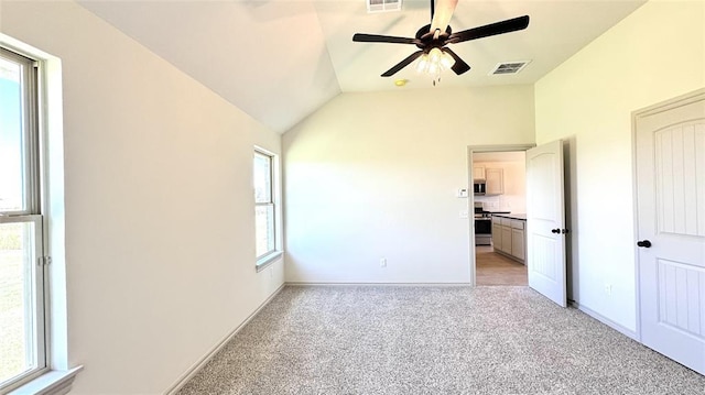 unfurnished bedroom featuring ceiling fan, light colored carpet, vaulted ceiling, and multiple windows