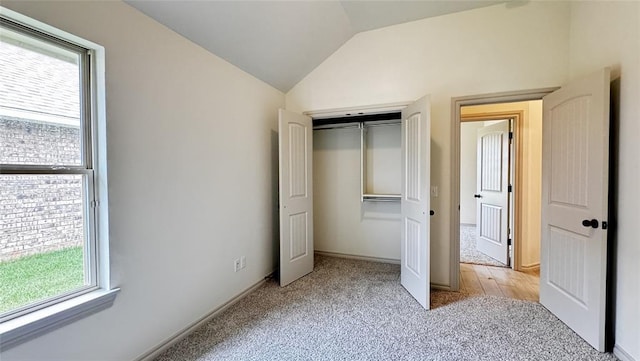 unfurnished bedroom featuring light colored carpet, multiple windows, a closet, and vaulted ceiling