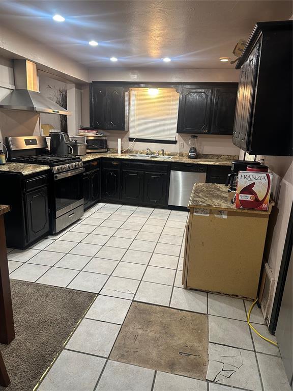 kitchen featuring sink, light tile patterned flooring, wall chimney exhaust hood, and appliances with stainless steel finishes