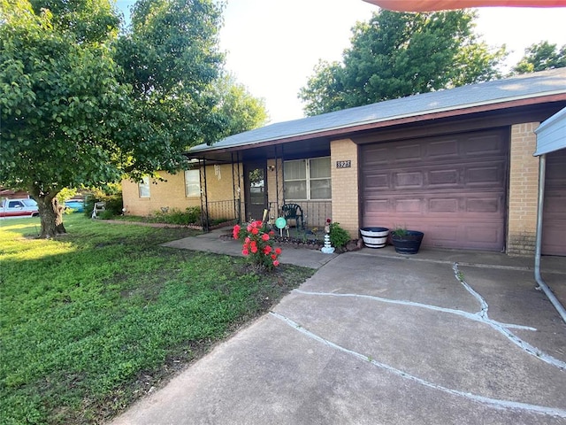 single story home with brick siding, a front yard, a porch, an attached garage, and driveway