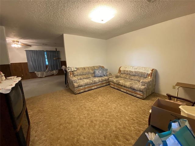 carpeted living area with a textured ceiling and ceiling fan