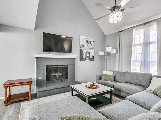 living room with ceiling fan, light hardwood / wood-style floors, high vaulted ceiling, and a brick fireplace