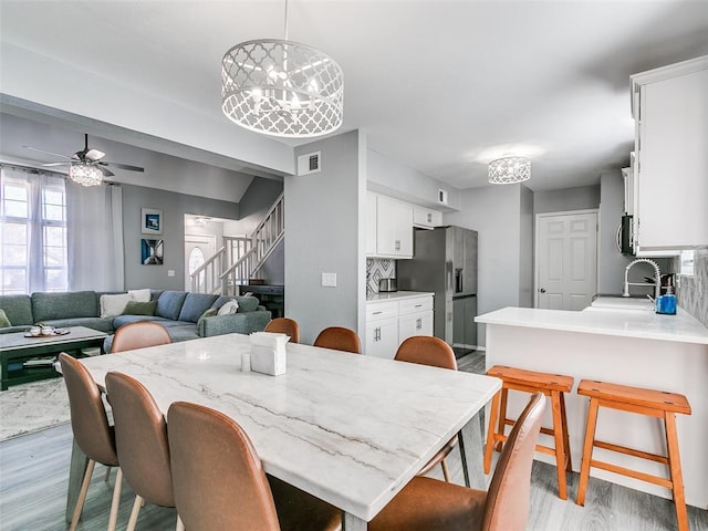 dining area with ceiling fan, sink, and light hardwood / wood-style flooring