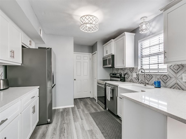 kitchen featuring white cabinets, stainless steel appliances, light stone counters, and tasteful backsplash