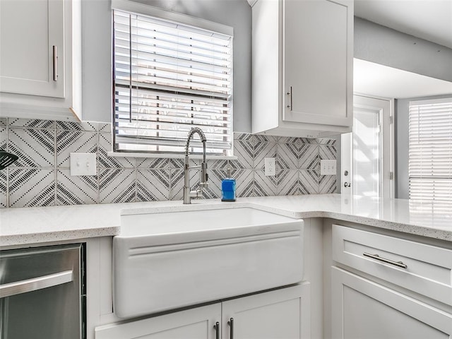 kitchen featuring sink, white cabinets, decorative backsplash, and light stone countertops